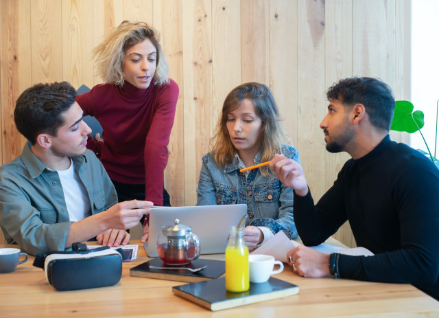 Quatro pessoas conversam sentadas à mesa em torno de um teste DISC.