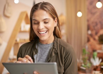 Jovem sorridente com computador na mão a abrir negócio online.